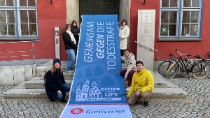 Greifswald ist Mitglied im Bündnis Städte gegen die Todesstrafe - Flagge vor dem Rathaus, Foto Pressestelle (1) © Pressestelle Mitarbeitende mit der Flagge des Bündnisses Städte gegen die Todesstrafe vor dem Rathaus