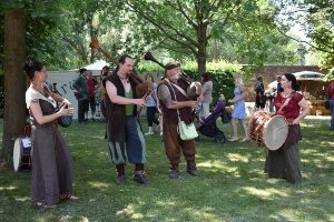 Musiker musizieren in Mittelalter-Kleidung auf der Anlage der Klosterruine.