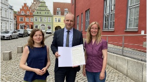 Anna Gatzke, Achim Lerm und Claudia Kowalzyck mit der Charta der Vielfalt vor dem Greifswalder Rathaus