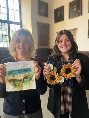 Die Städtebotschafterinnen Abigaël Landreau aus Angers (Frankreich) und Rosie Jones aus Derby (Großbritannien) zeigen ihre selbstgestalteten Quadrate