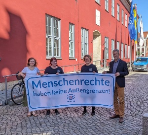 Die Gründungsmitglieder und Greifswalds Oberbürgermeister halten vor dem Rathaus ein Banner mit dem Slogan "Menschenrechte haben keine Außengrenzen" hoch