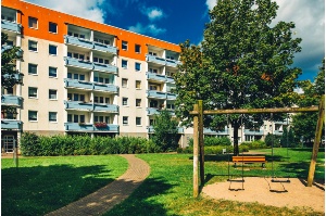 Eine Schaukel und ein Baum stehen vor einem Wohnblock mit Balkonen in Schönwalde II